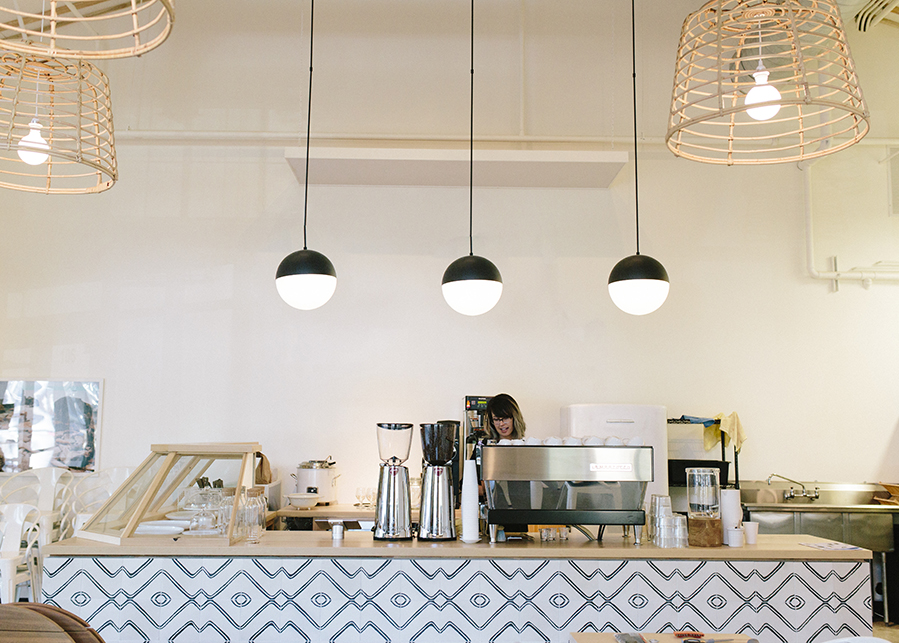 The coffee bar, pastry case, and minimalist light fixtures featuring minimalist ironwork and woven shades